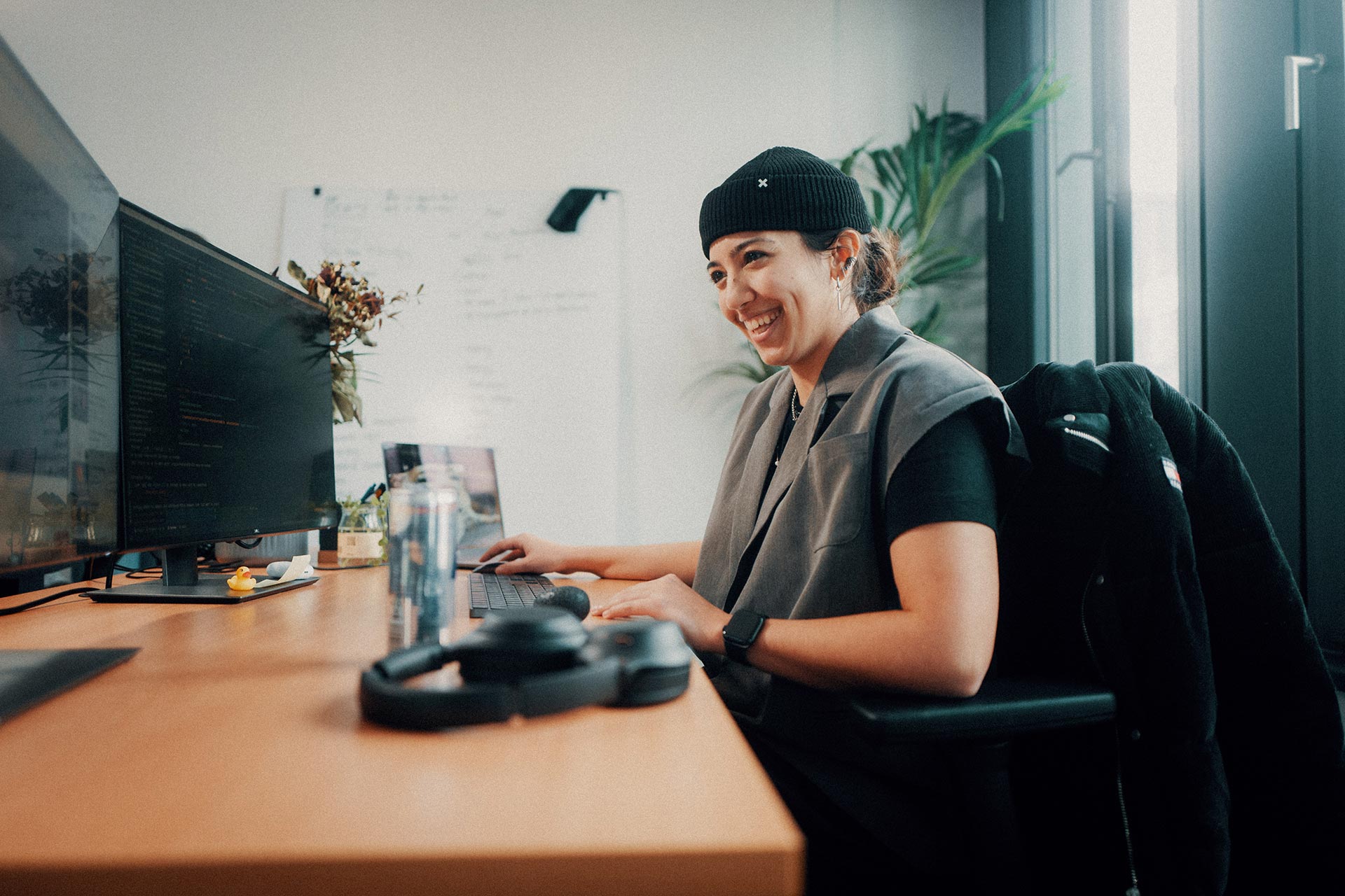 Smiling female developer sitting in front of two monitors